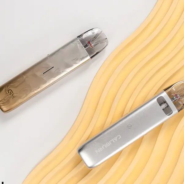 Uwell Caliburn G4 Mini Pod Kit in zwei Metallic-Varianten – Bronze-Gold und Silber, liegend auf hellem Untergrund