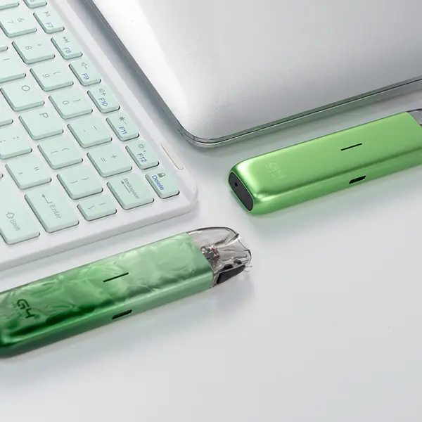 Uwell Caliburn G4 Mini Pod Kit in Grün neben Laptop-Tastatur, Lifestyle-Aufnahme